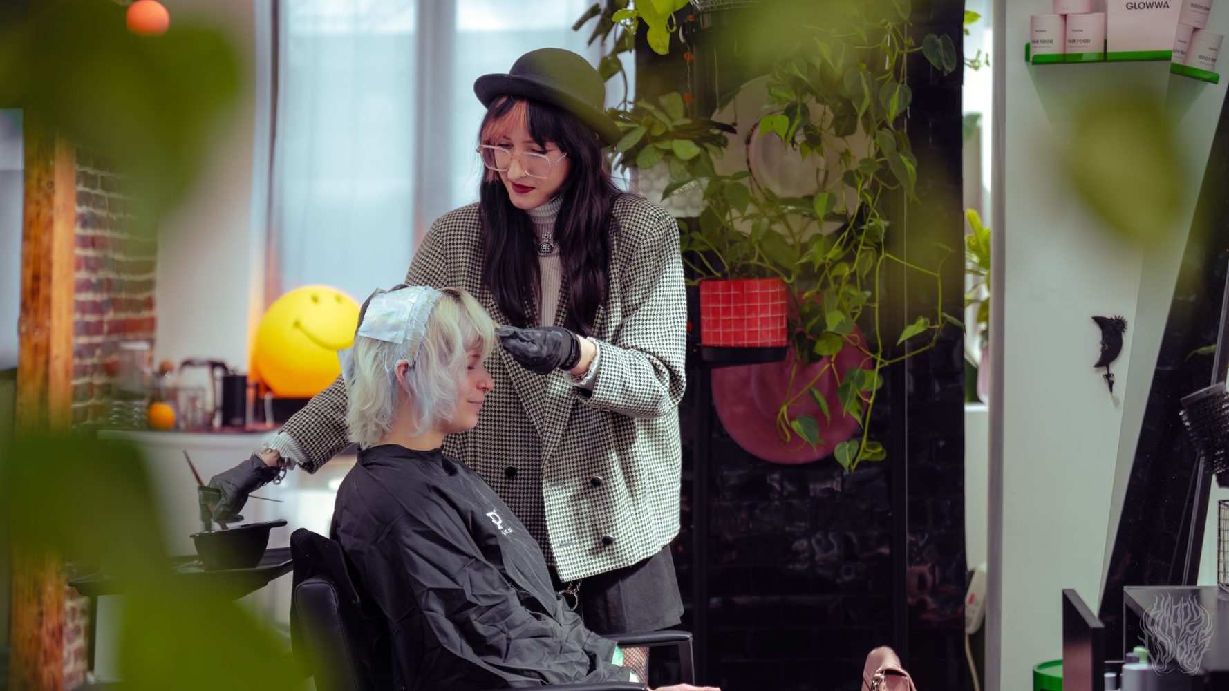 A Happy Colors stylist colouring a client's hair among the salon plants