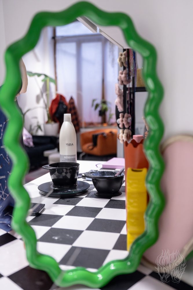 A wavy green mirror reflecting the Happy Colors salon